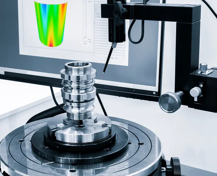 Stainless steel machined part on a rotary measuring stage with a probe and roundness graph on monitor