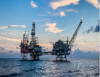 Offshore oil and gas drilling platforms at sea at sunset
