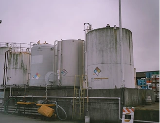 Large cylindrical storage tanks with hazard placards at a chemical storage facility