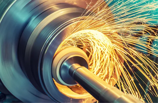 Sparks flying as a grinding wheel finishes a rotating steel shaft