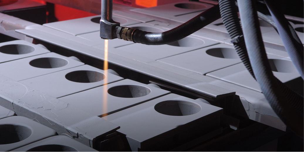 Thermal spray gun coating gray metal parts with a glowing spray stream