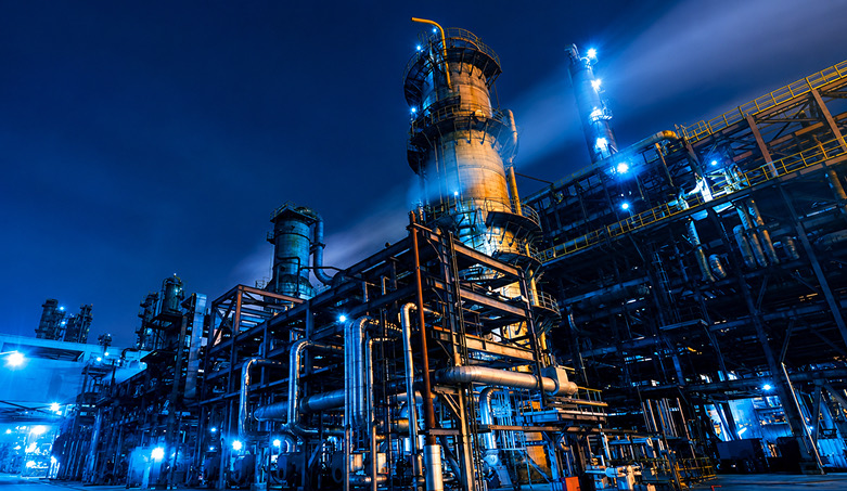 Refinery towers and piping lit with blue lights at night