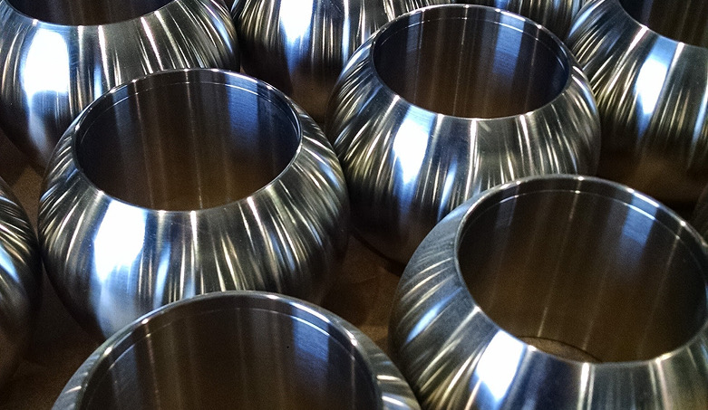Polished stainless steel spherical valve balls with open bores, arranged in rows