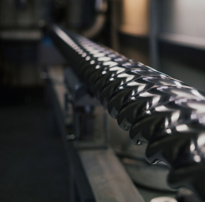 Polished helical drilling shaft with spiral flutes on a workbench