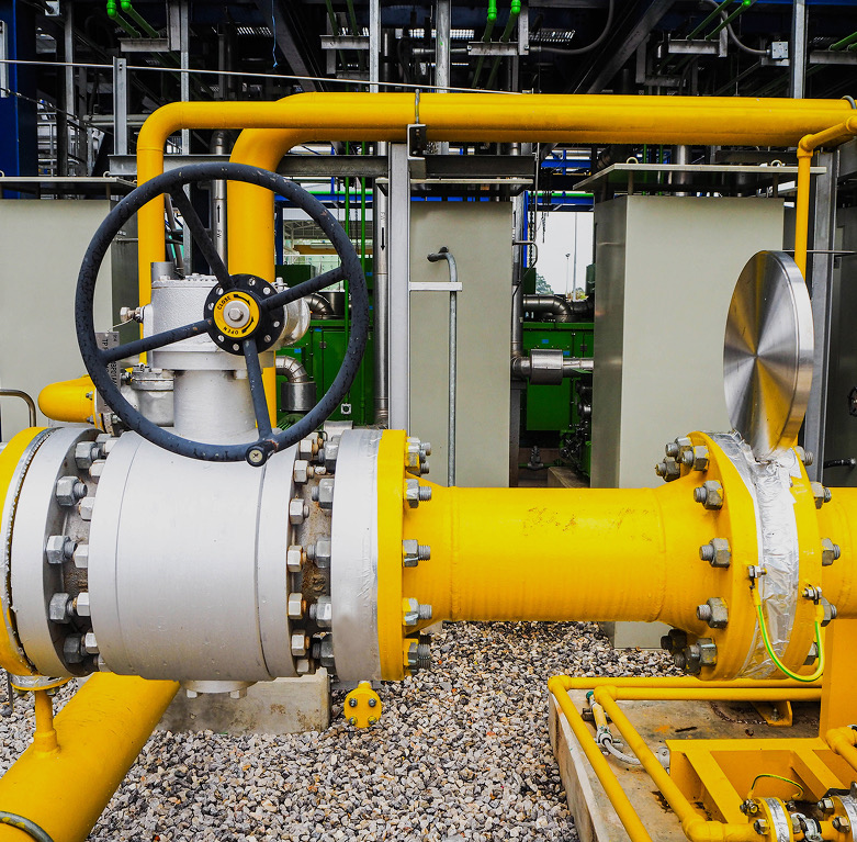 Ball valve with black handwheel and yellow bolted pipework at an industrial plant