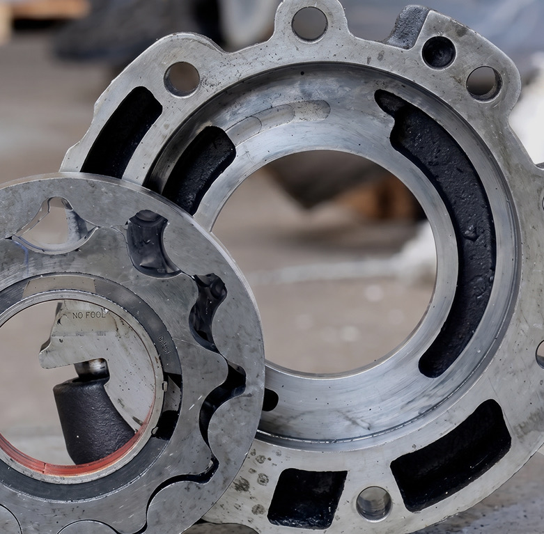 Two machined cast-metal pump housing components with bolt holes and internal channels